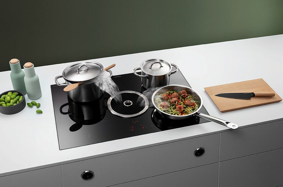 Modern BORA induction cooktop with integrated downdraft extractor, shown with pots and pan releasing steam in a minimalist kitchen.