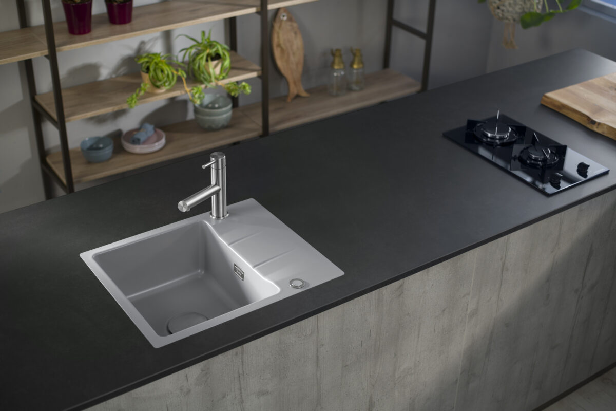 Systemceram ceramic sink in matte "Alu" finish on dark countertop, styled for modern kitchens.
