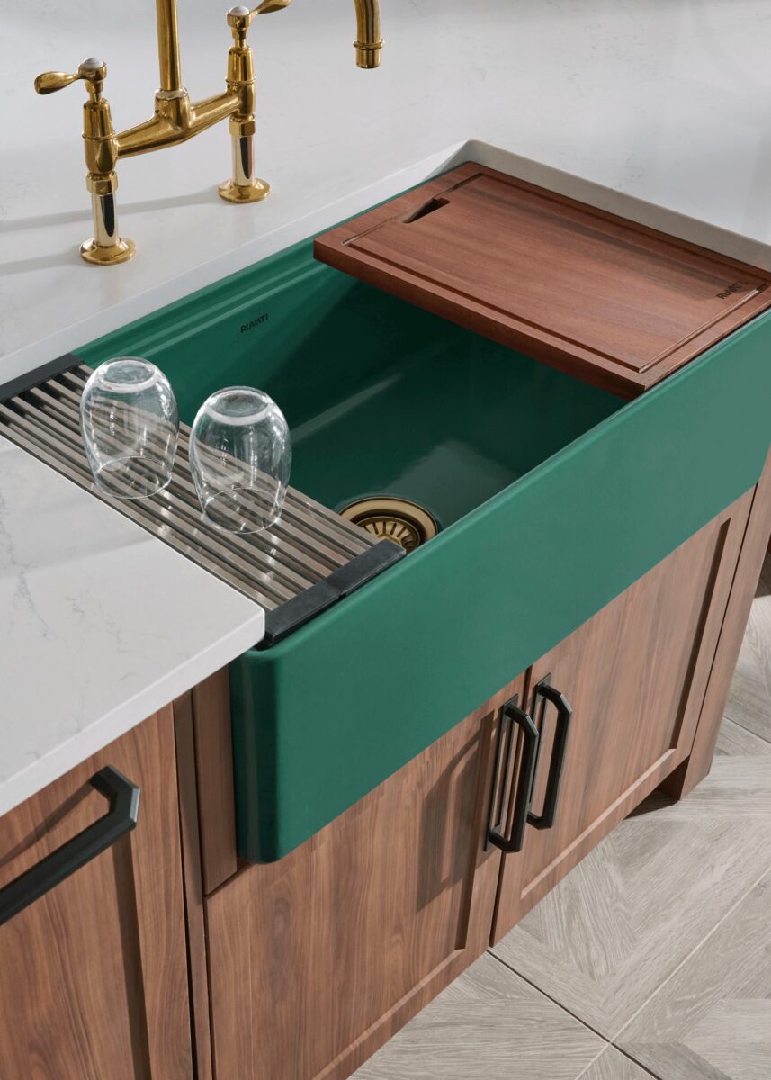 The Fiore sink in emerald green features a solid fireclay body, paired with a brass faucet and dark walnut accessories for a rich, European-inspired kitchen aesthetic. Copyright: Ruvati