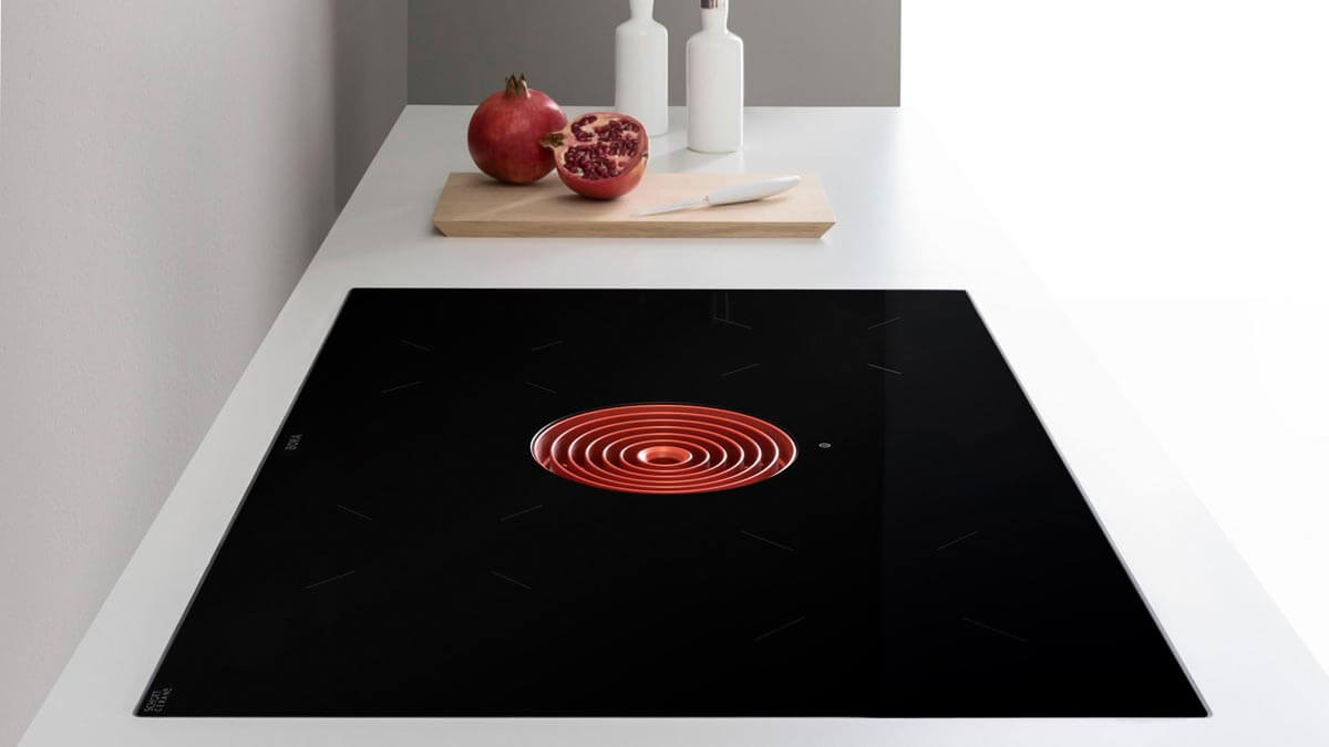 Modern kitchen with BORA Pure cooktop featuring a red circular downdraft extractor in a minimalist white countertop.