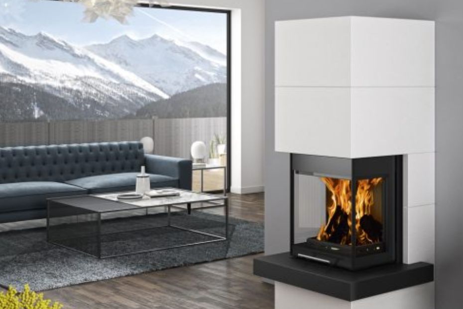 Open living area with large windows, blue sofa, and white cladding on an ORANIER fireplace; modern loft-style aesthetic.