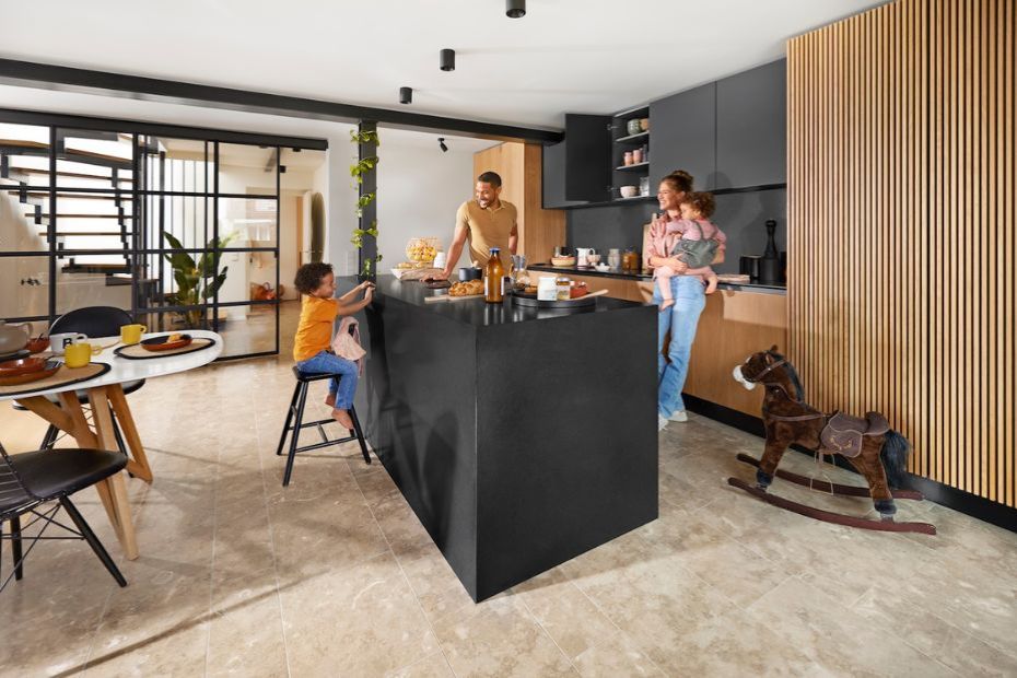 Family spending time together in a modern kitchen with a black island, wood cabinetry, and open dining area.