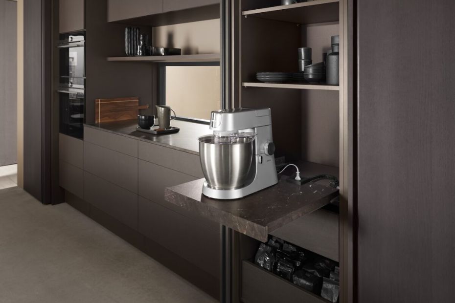Pull-out shelf inside a tall kitchen cabinet displaying a stand mixer ready for use.