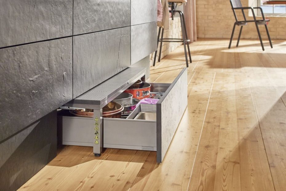 Toe-kick drawer SPACE STEP from BLUM pulled open beneath lower cabinets, showing additional storage for pots and kitchen accessories.