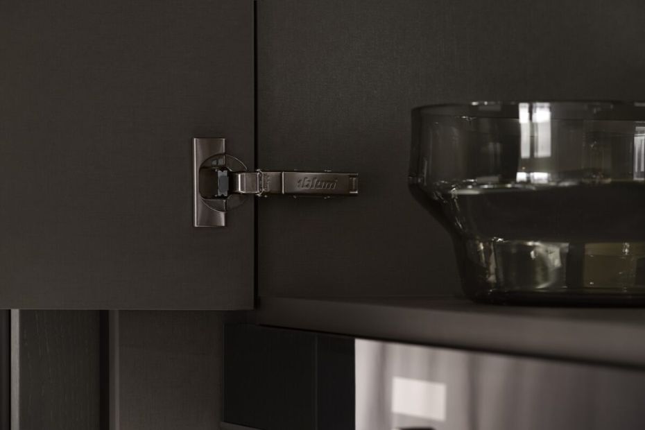 Close-up of a dark CLIP top BLUMOTION Onyx hinge on a modern kitchen cabinet door.