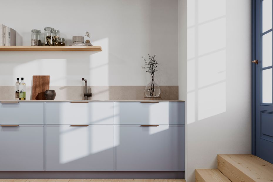 Detail view of a modern kitchen with light fjord blue cabinets, wood handles, and a natural stone countertop