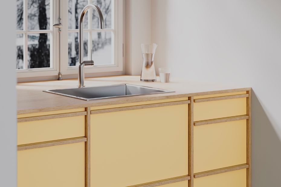 Modern kitchen with matte wax yellow cabinet fronts, natural wood textures, and soft daylight under a large window